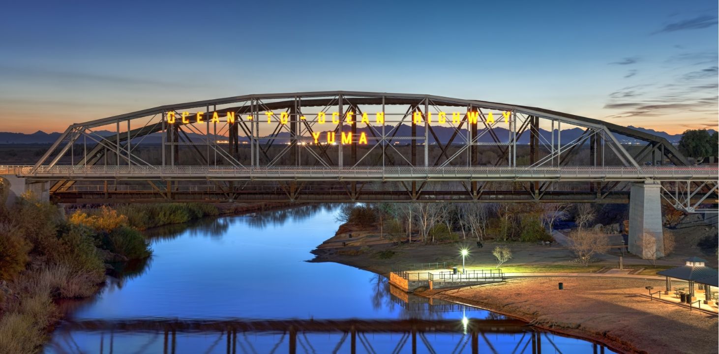 Picture of a bridge over water with a bridge reflection in sunset