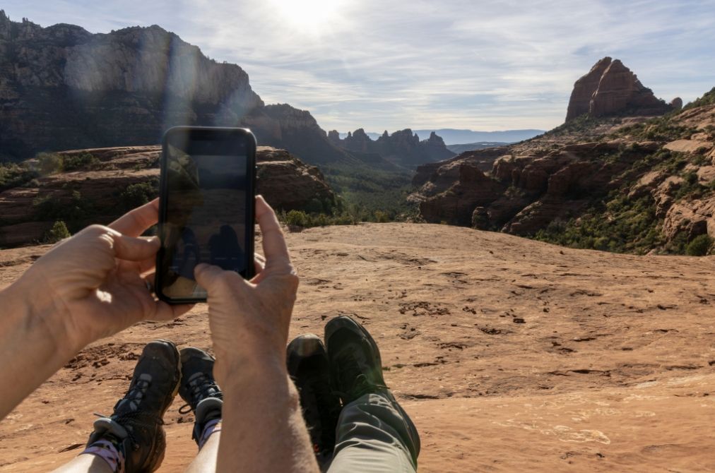 Hands holding up a phone taking a picture of the land