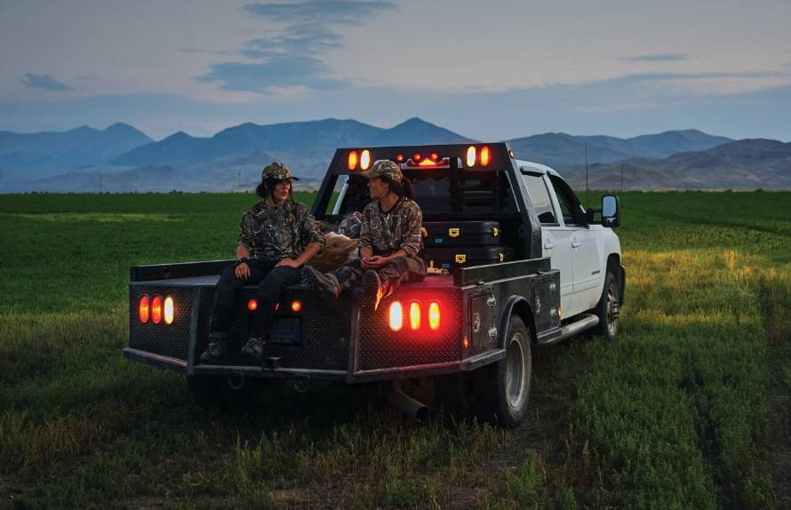 Two people sitting on the back of the truck